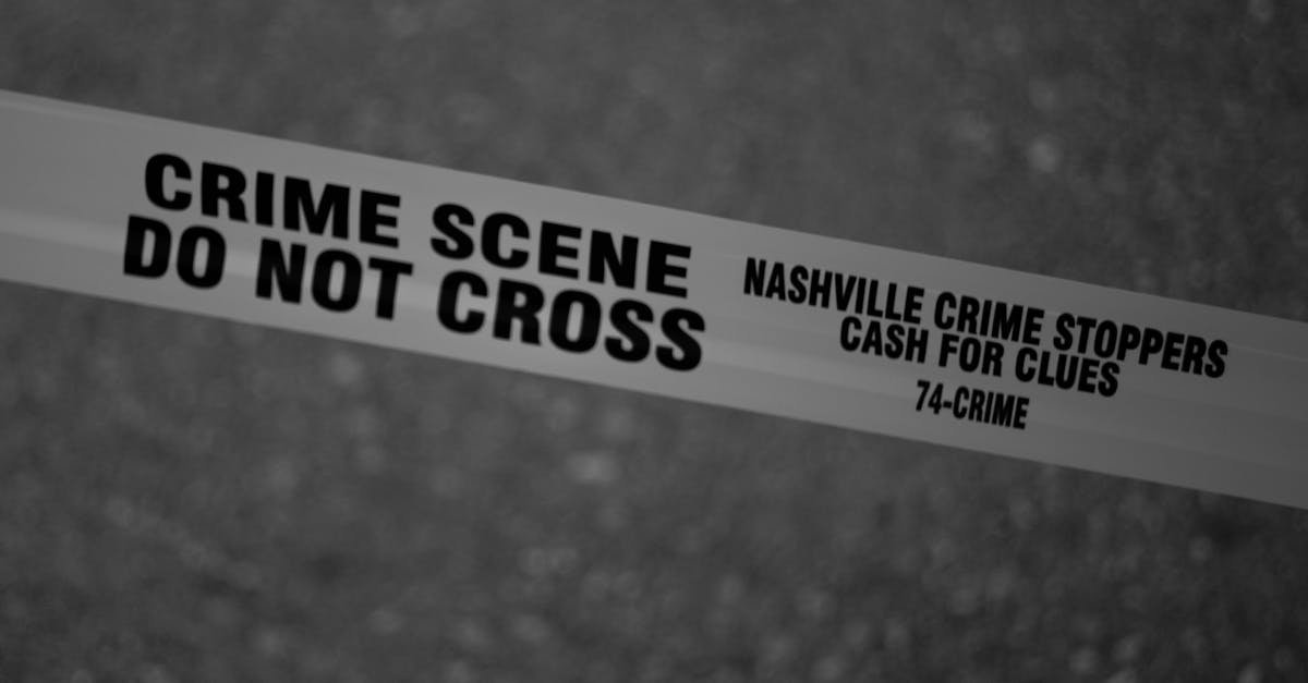 Crno-bijela fotografija prikazuje policijsku vrpcu s natpisima MJESTO ZLOČINA ZABRANJEN PRELAZAK i NASHVILLE CRIME STOPPERS NOVAC ZA TRAGOVE 74-ZLOČIN razapetu preko zamućene pozadine, što ukazuje na ograničeno područje istrage.